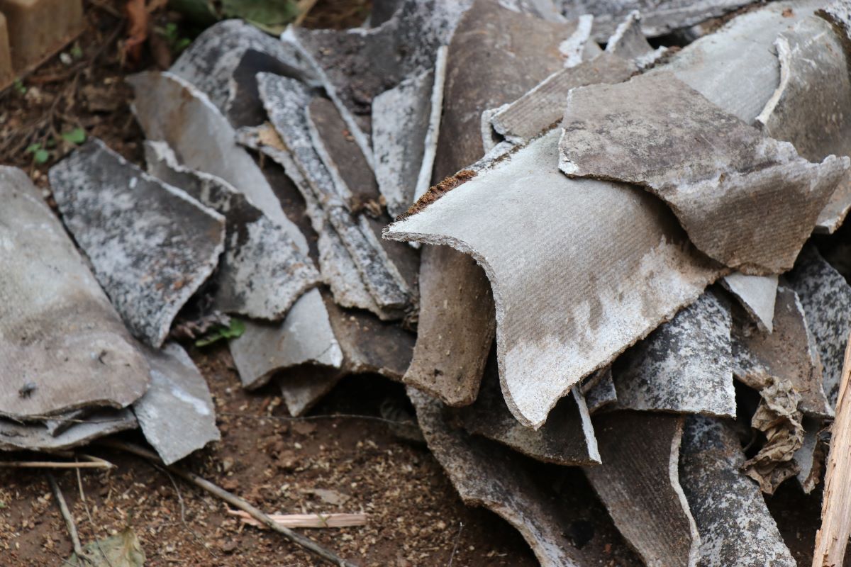 group of broken and fibrous slice of corrugated asbestos cement sheets. asbestos sheets after demolition